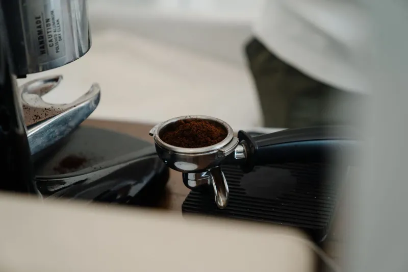 Verschmutzter Espresso-Siebträger mit braunen Kaffeöl-Rückständen rund um den Siebkorb