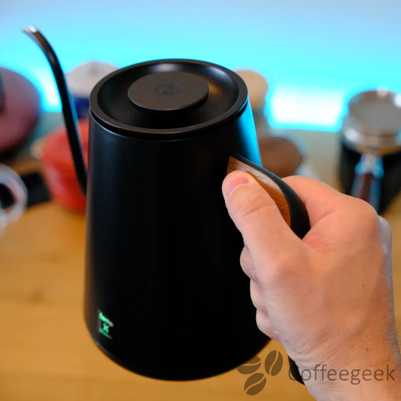 Hand hält den Timemore Fish PRO X an der Daumenauflage aus Holz
