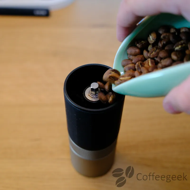 Versement des grains de café dans le moulin Wacaco Exagrind